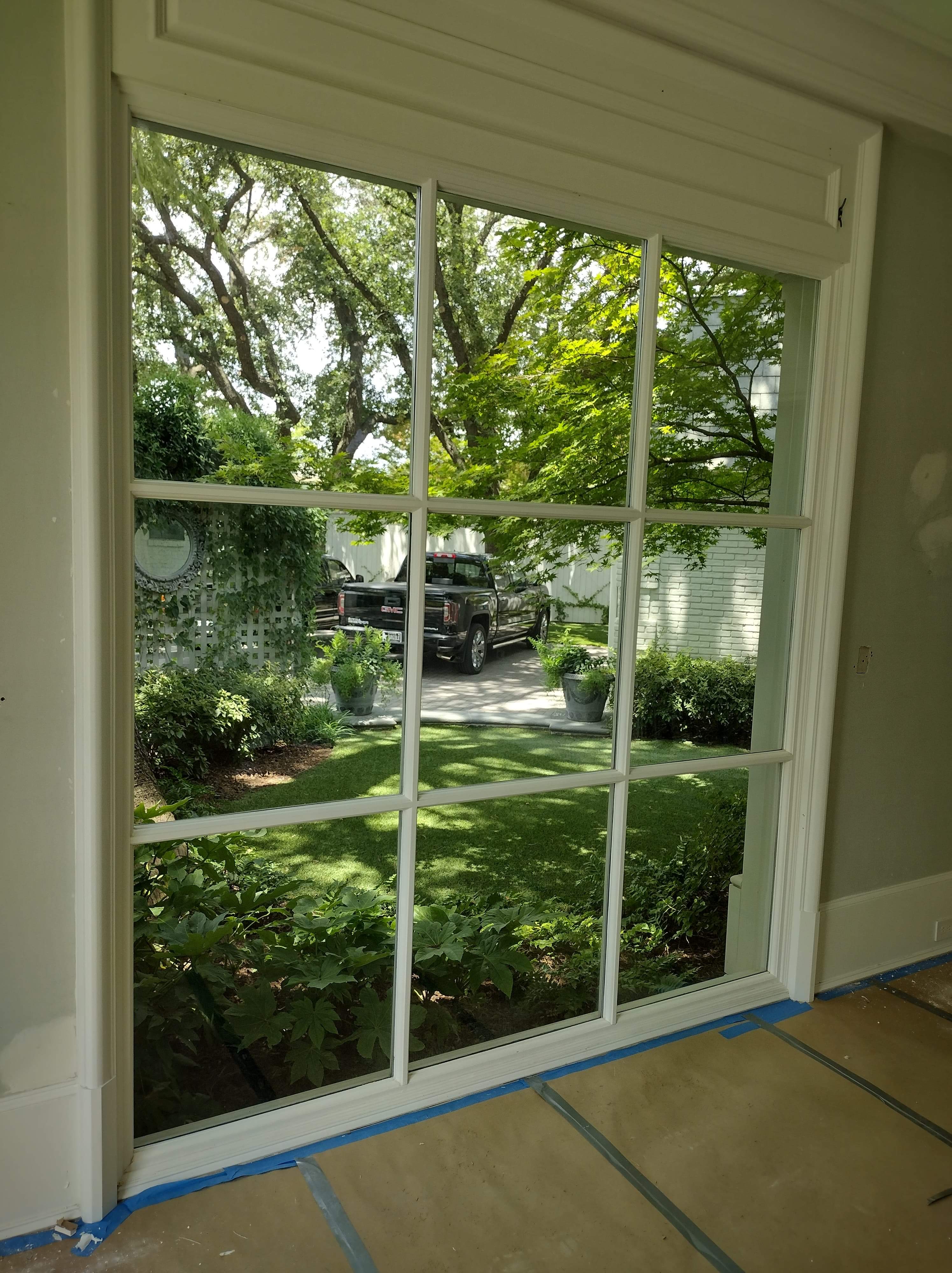 Interior view through tinted grid windows looking out to garden