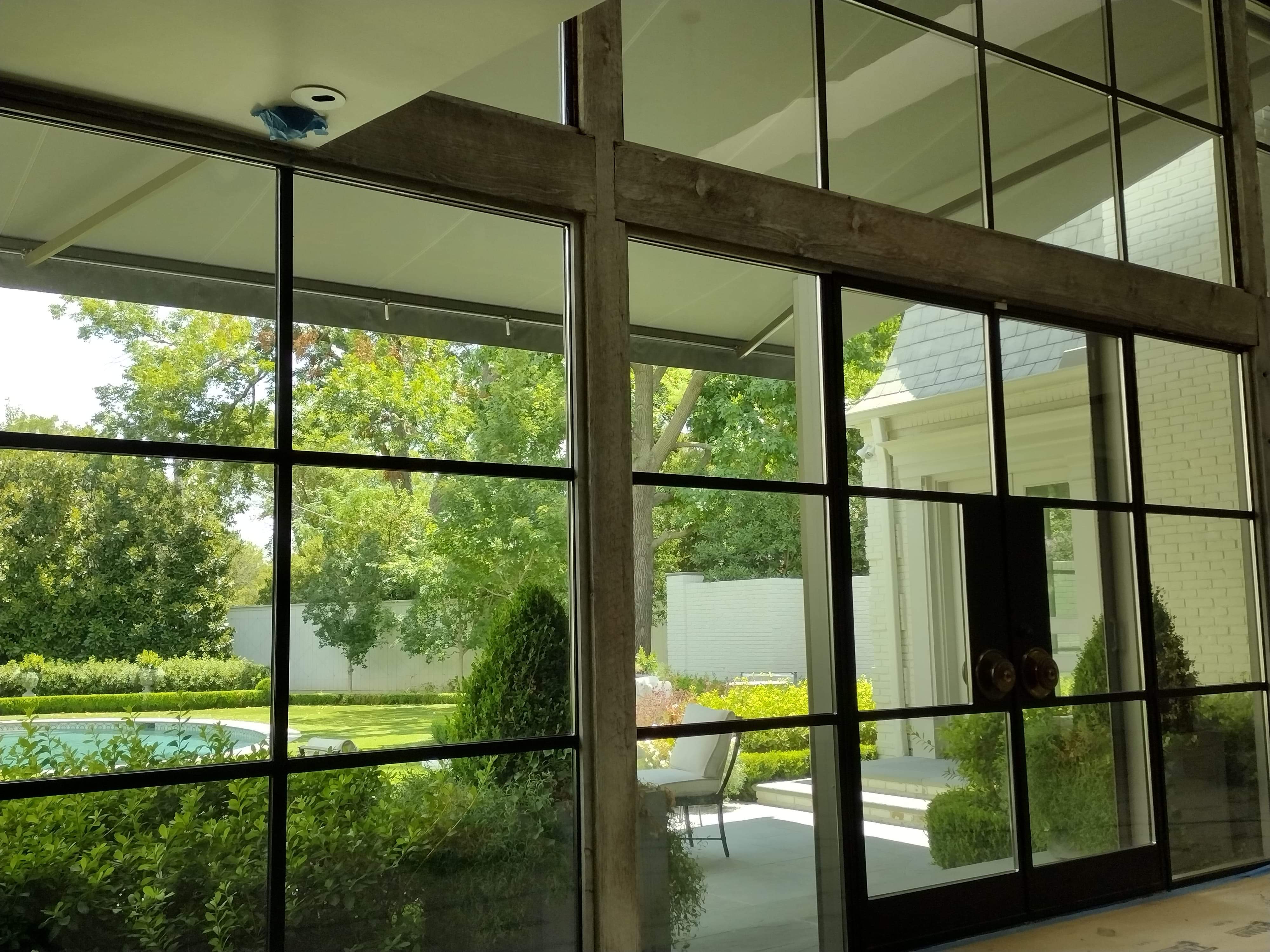 Interior floor-to-ceiling tinted windows overlooking manicured garden